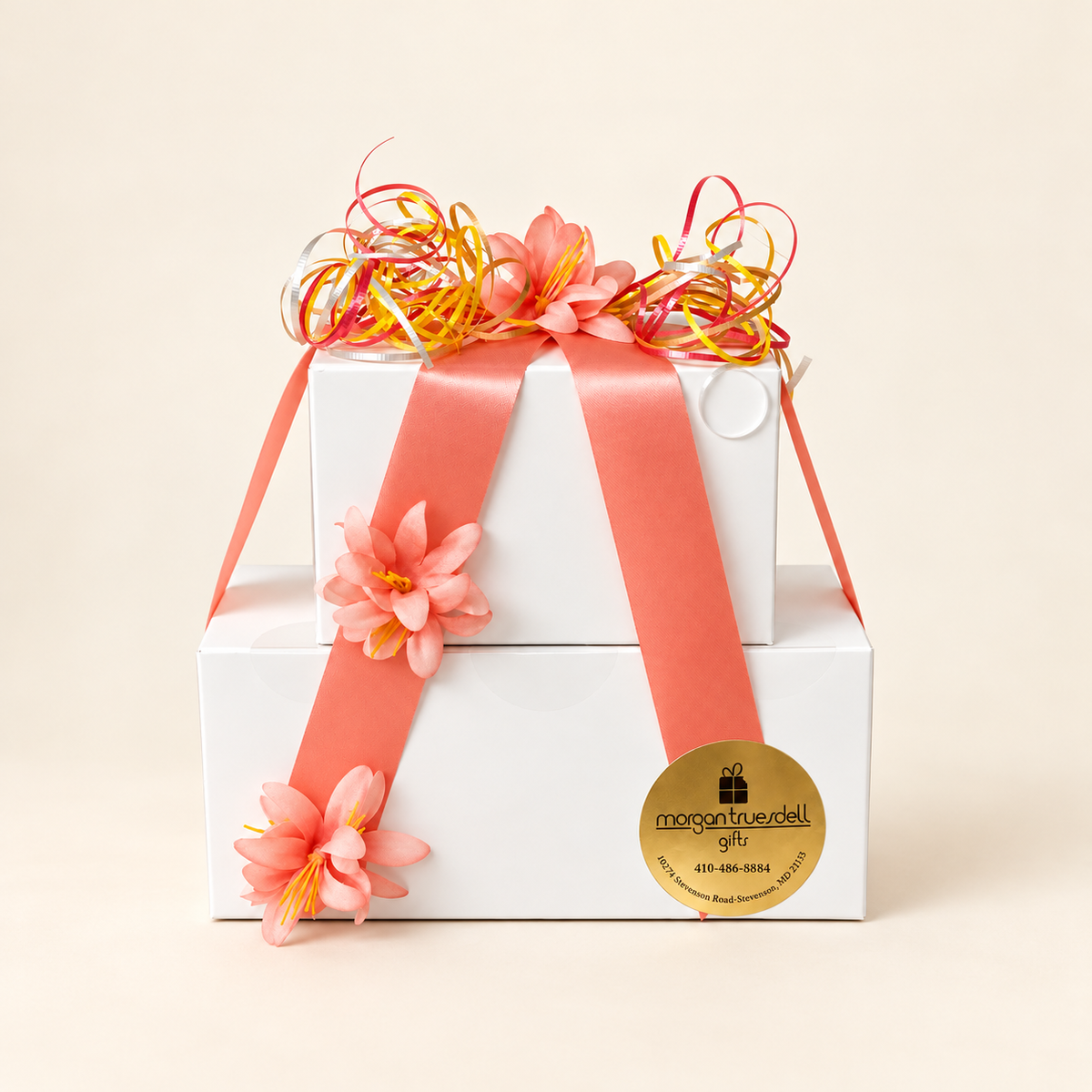 Hostess gift boxes filled with assorted chocolates, wrapped with coral ribbon and floral accents