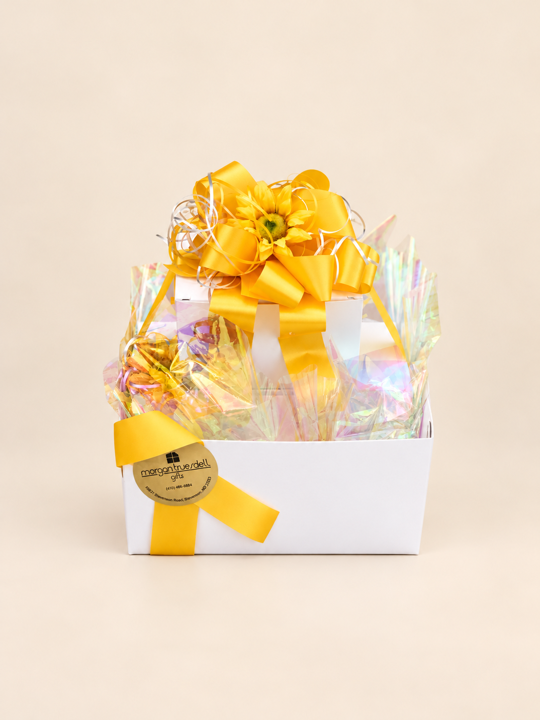 Tiered gift box with assorted chocolates and candy, wrapped with yellow ribbon.