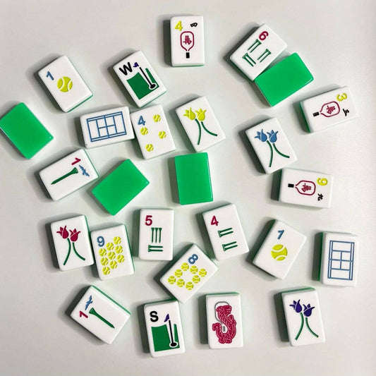 Scattered mahjong tiles with golf- and tennis-themed artwork