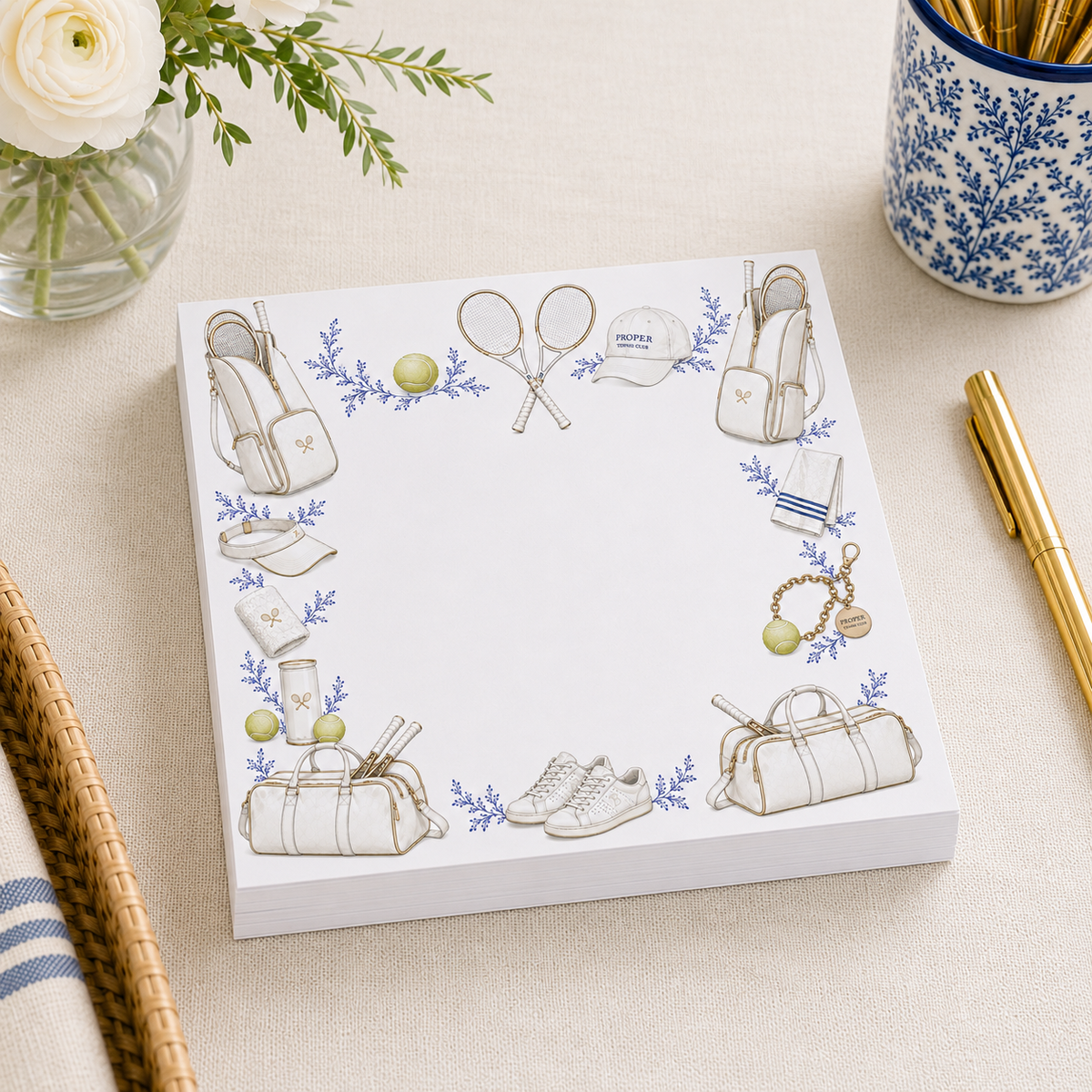 Close-up of acrylic notepad holder with tennis-illustrated notepads and gold pen