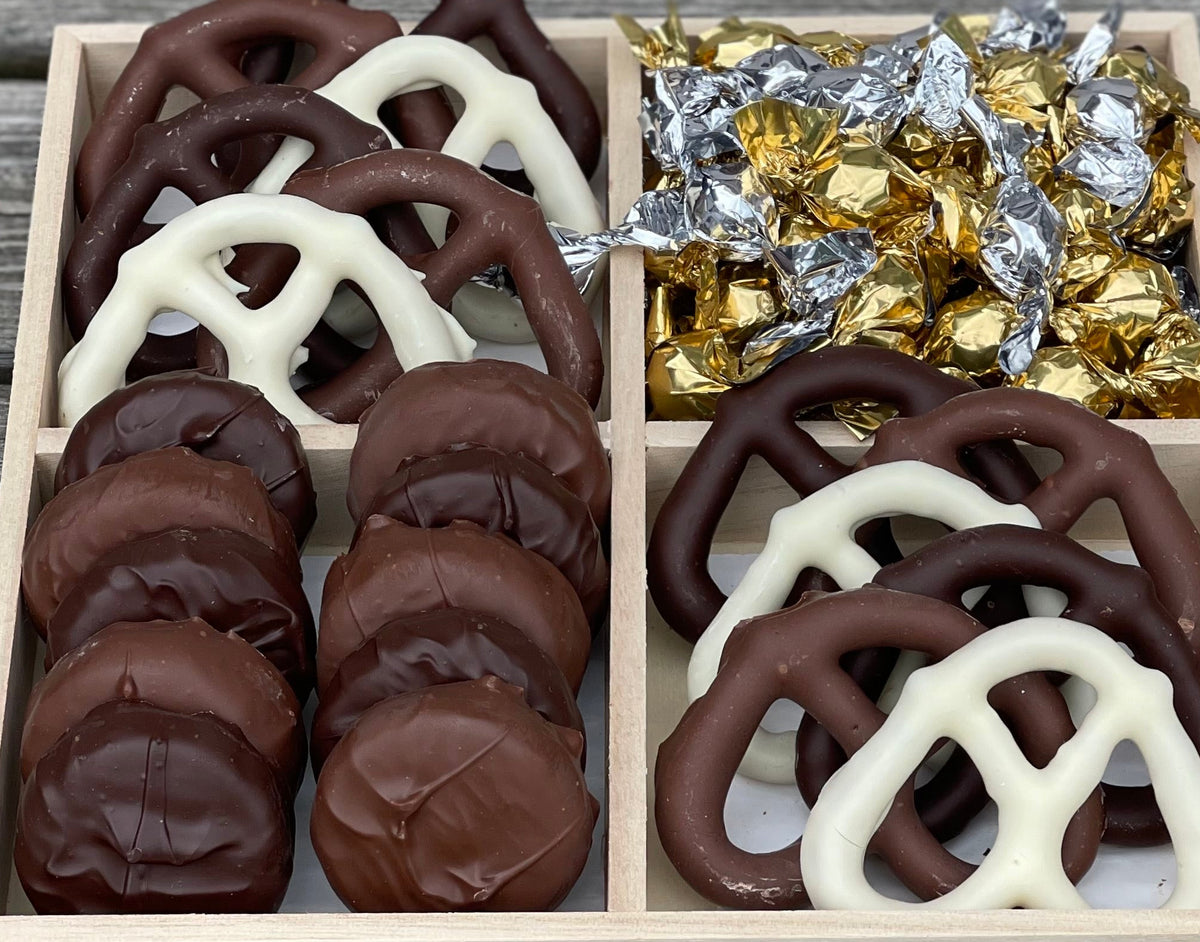 Wooden four-compartment gift box with chocolate pretzels, foil-wrapped candies, and cookies