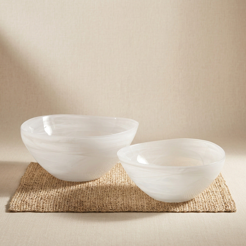 Two white alabaster glass bowls with swirled texture on a woven jute mat