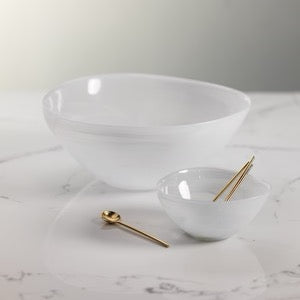 White alabaster glass bowl styled on marble with matching small bowl and gold spoons