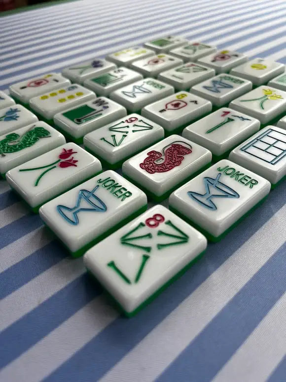 Mahjong tiles lined in rows on a blue-striped mat, viewed at an angle