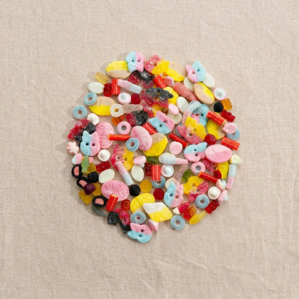 Circular pile of colorful Swedish gummy candies on beige linen
